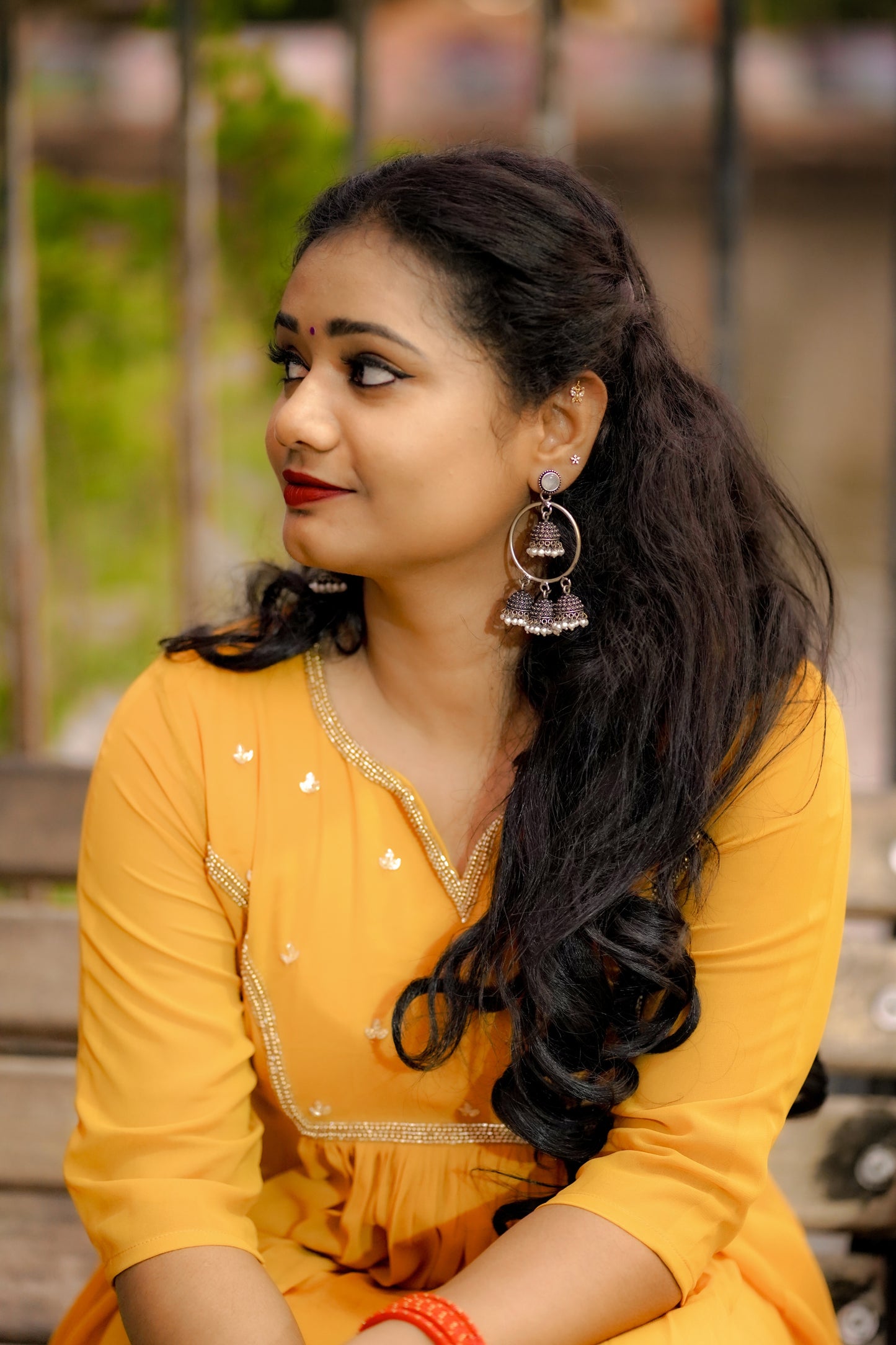 Woman wearing a mustard yellow below‑knee midi dress with hand‑beaded yoke in natural outdoor setting